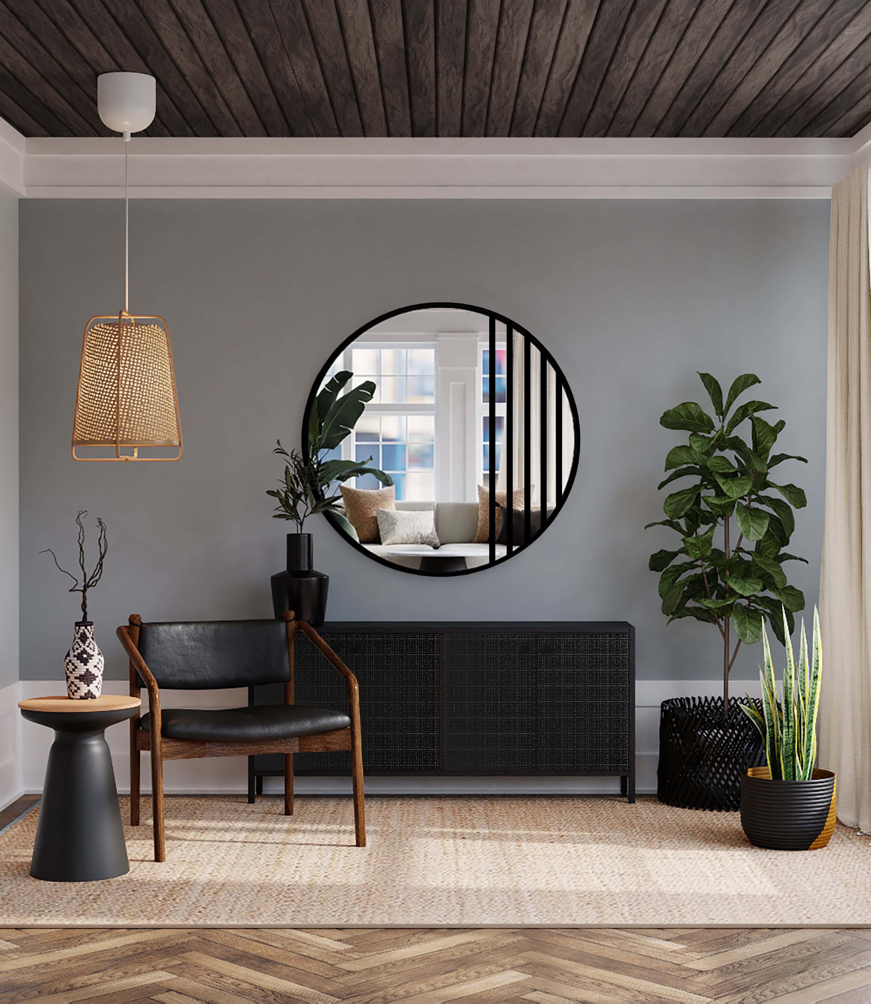 Oglindă rotundă cu grilaj metalic negru, montată pe un perete gri într-un interior modern, decorat cu mobilier din lemn, accente negre și plante verzi.