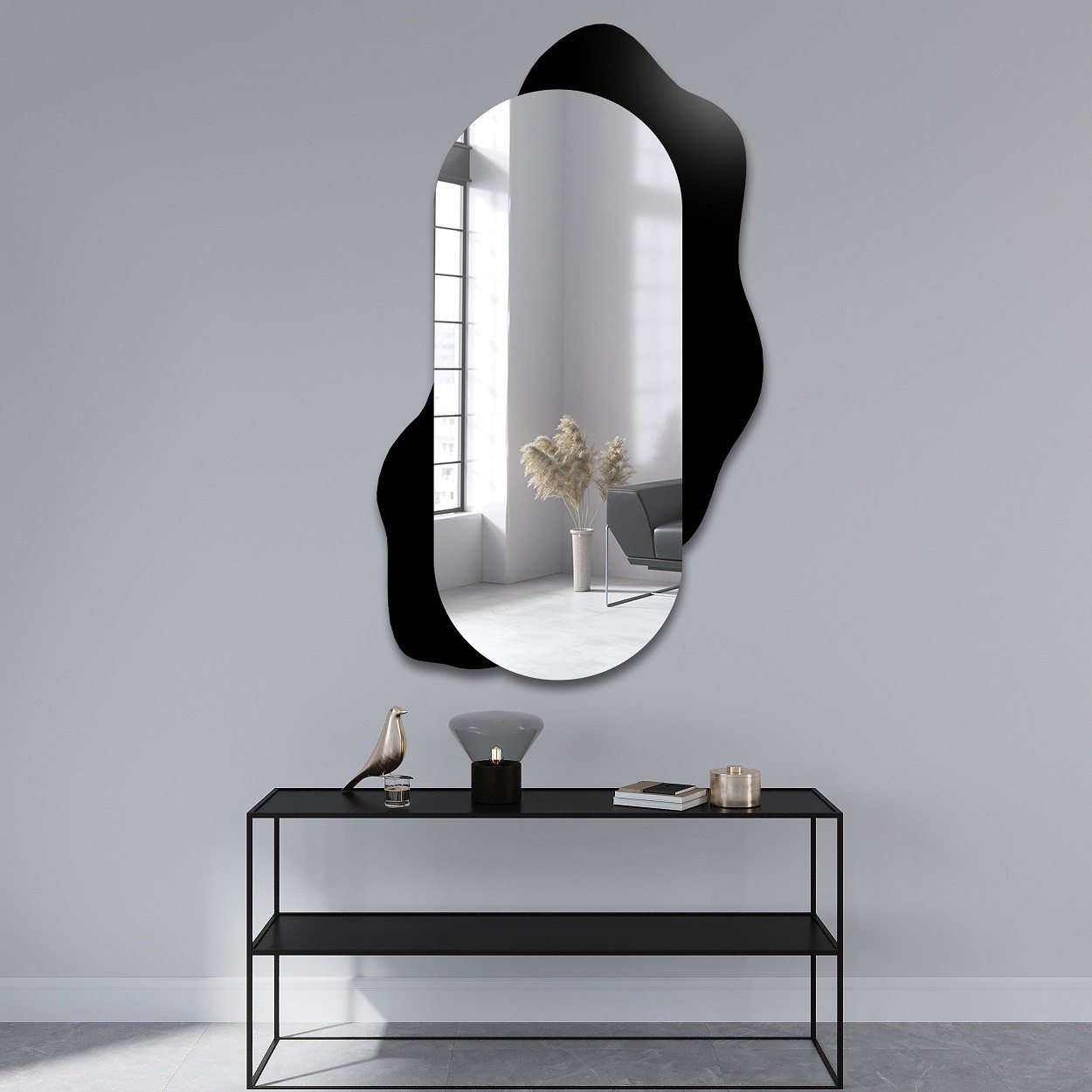 Oglindă ovală cu fundal negru de formă organică, montată pe un perete într-un interior modern, alături de o consolă metalică elegantă și elemente decorative minimaliste.